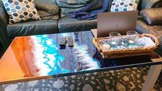 a glass table topped with a laptop computer next to a blue couch and coffee table