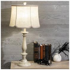 a white lamp sitting on top of a wooden table next to books and a toy truck