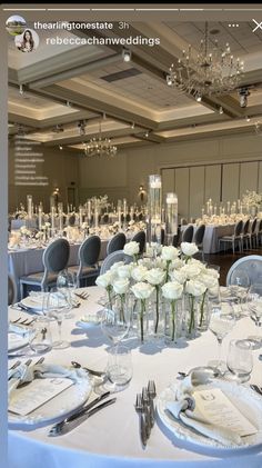 a table set up for a wedding with white flowers in vases and place settings