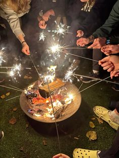 people standing around a cake with sparklers on it