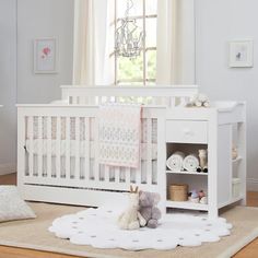 a white crib with a teddy bear and stuffed animal on the floor next to it