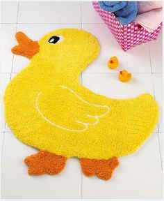 a yellow rubber ducky bath mat on the floor next to a pink tissue paper bag