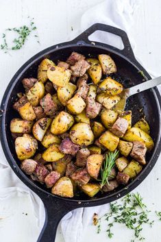 a skillet filled with cooked potatoes and garnished with parsley on the side