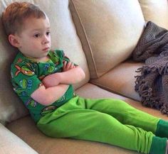 a little boy sitting on top of a couch next to a black dog and caption that reads, yeah fine