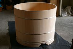 a large wooden barrel sitting on top of a black piece of paper in a room