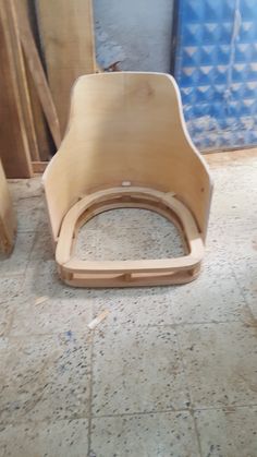 a wooden chair sitting on top of a floor next to some wood planks and plywood