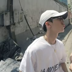 two young men standing next to each other on a sidewalk with buildings in the background