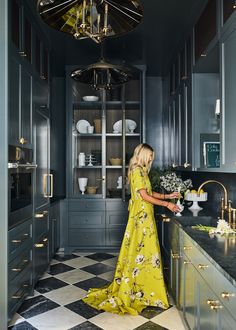 a woman in a yellow dress is standing at the kitchen counter with flowers on it