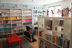 a room filled with lots of books and toy figurines on the shelves next to each other