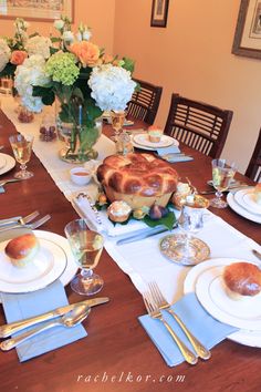 a table set with plates, silverware and flowers in vases on the table