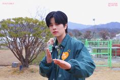 a young man holding a microphone in his right hand and wearing a green jacket with an orange emblem on it