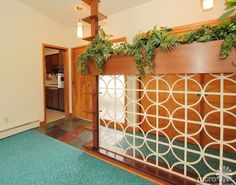 an empty living room with green plants on the wall and blue carpeted flooring