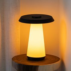 a table lamp sitting on top of a wooden stand next to a curtained wall