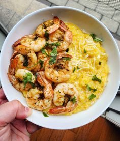 a person holding a bowl of shrimp and grits