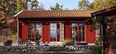 a red house with two doors and windows on the outside, surrounded by greenery