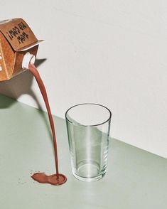 a glass filled with liquid sitting on top of a table next to a cardboard box