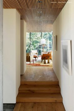 an open hallway with wooden flooring and white walls, leading to the living room