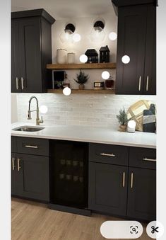 a kitchen with black cabinets and white counter tops, lights above the sink are on