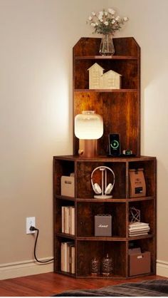 a wooden shelf with books and other items on it in a living room next to a white wall