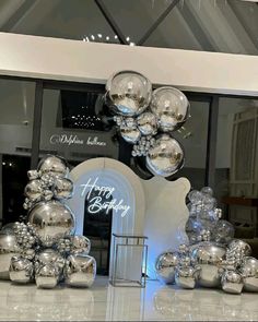 an assortment of shiny silver objects on display in front of a store window with the words happy birthday written on it