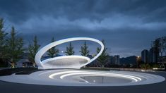 an artistic sculpture in the middle of a park at night with buildings in the background