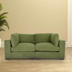 a green couch sitting next to a potted plant