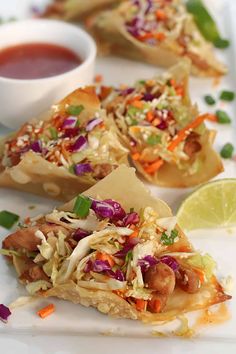 three pieces of flatbread with coleslaw and lime on top, next to a small bowl of dipping sauce