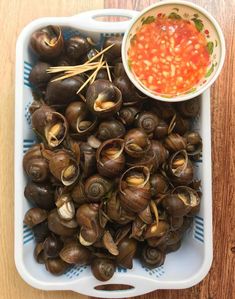 a bowl filled with clams next to a small bowl of sauce