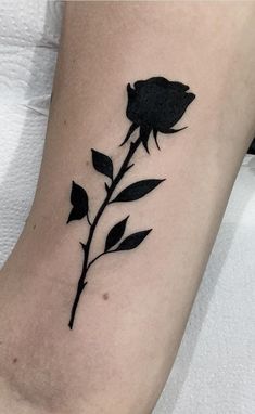 a black rose tattoo on the right side of the leg, with leaves growing out of it