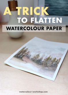 a white vase sitting on top of a table next to a watercolour paper