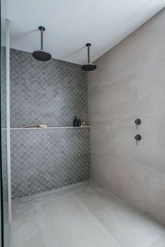 a walk in shower sitting next to a white tiled wall with two faucets