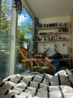 a bedroom with a bed, desk and bookshelf next to a large window