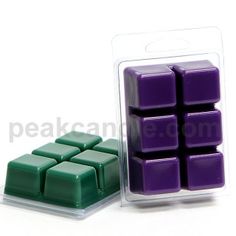 a purple and green wax cube in a plastic container next to it's packaging