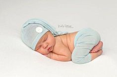 a newborn baby wearing a blue hat and diaper is sleeping on his side with its eyes closed