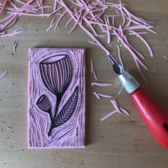 a pair of pink scissors next to a piece of art