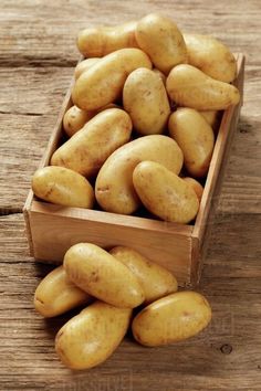 a wooden box filled with potatoes on top of a table