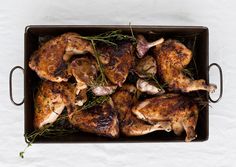 chicken in a roasting pan with herbs on the side