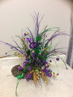 a purple and green flower arrangement sitting on top of a table