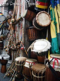 several drums and drum sticks hanging from the side of a building with other musical instruments