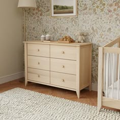 a baby's room with floral wallpaper and a crib in the corner