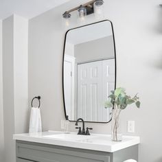 a bathroom with a large mirror above the sink and a white toilet next to it