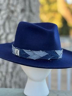 Designer choice!! Take a look at this fun denim blue adjustable hatband with different colors of denim that really make this hatband pop on any style/color of hat. The band is 22.5" x 1.25" and has adjustable navy-blue suede ties in the back so it can fit hats from 22.5-34". The band is secured by two gold tie clamps in the back to give it a nice, finished look. The hat band has been sewn together and treated with fray protector to help keep this hatband looking good for years to come. To comple Denim Blue Hat With Curved Brim, Adjustable Denim Blue Wide Brim Hat, Adjustable Wide Brim Denim Blue Hat, Denim Blue Wide Brim Hat With Adjustable Fit, Blue Denim Brimmed Hat, Trendy Blue Brimmed Fedora, Adjustable Blue Felt Hat With Curved Brim, Adjustable Denim Blue Hat, Adjustable Wide Brim Blue Felt Hat