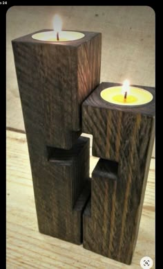 two wooden candles sitting on top of each other in front of a wood block sculpture