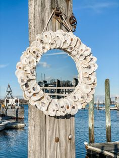 a mirror hanging on the side of a wooden pole next to a body of water