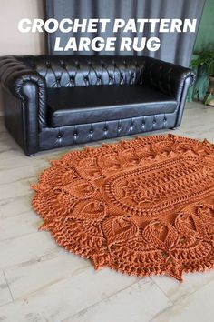 an orange crochet rug is on the floor next to a black leather couch