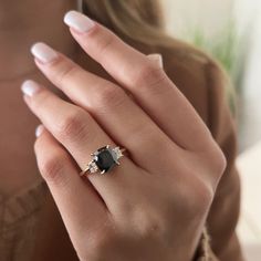 a woman's hand with a ring on it and a black diamond in the middle