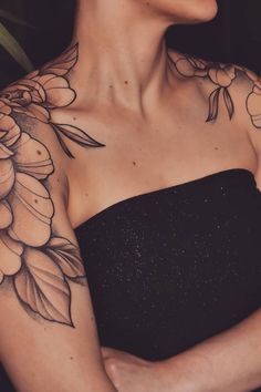 a woman wearing a black dress with flowers on her chest and arm tattooing it