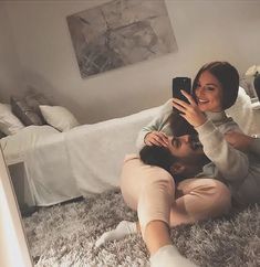 a man and woman laying on the floor taking a selfie