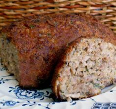 a meatloaf cut in half on a blue and white plate next to a basket