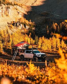 two pickup trucks parked in the woods with their camper attached to the back end